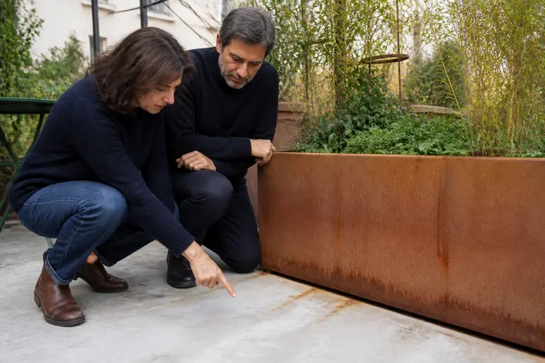 Observation des premières coulures de rouille sur un objet en acier corten entretien dans un jardin parisien.