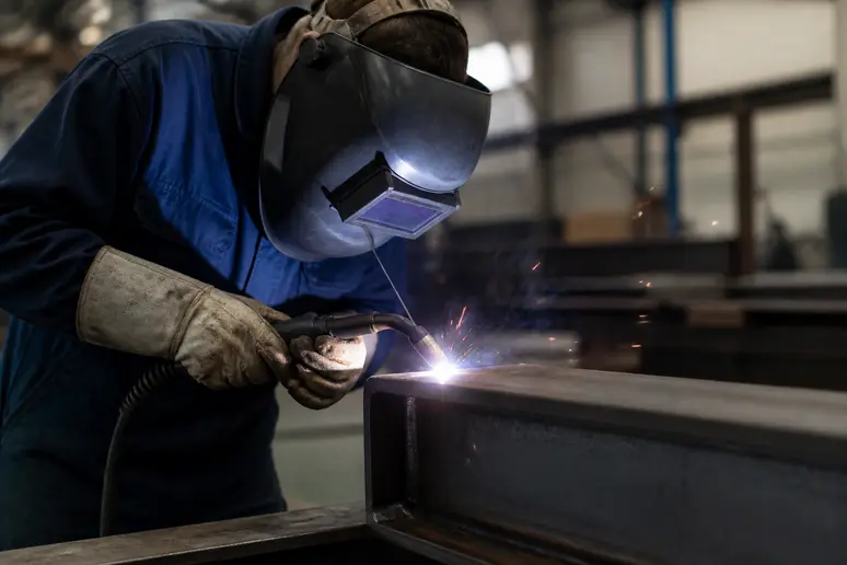 Opérateur qualifié réalisant une soudure sur un profilé en acier S355 en atelier