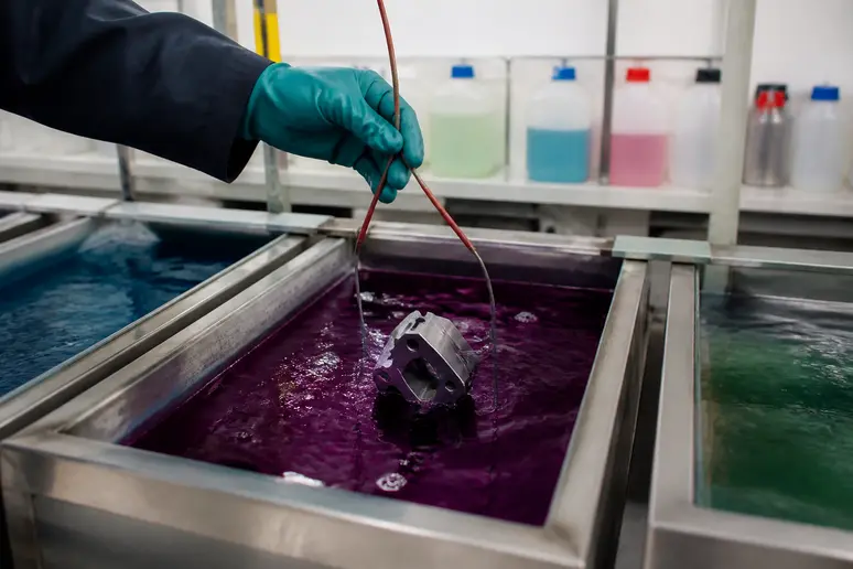 Pièce en aluminium dans un bain coloré lors de l'étape de coloration de l'anodisation aluminium.