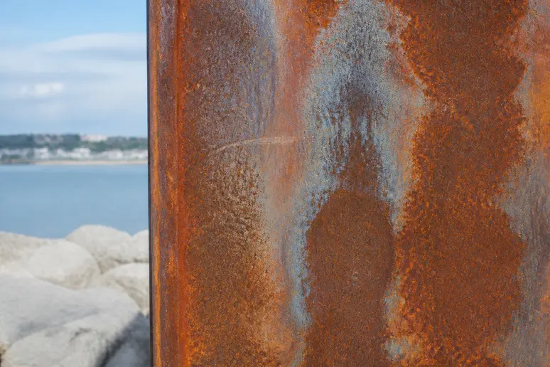 Panneau en acier corten présentant une corrosion irrégulière en ambiance saline côtière.