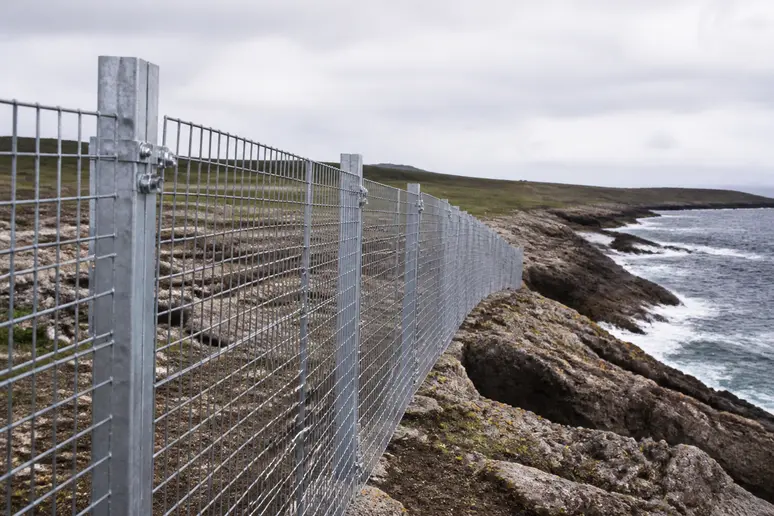Clôture en acier galvanisé installée durablement en bord de mer face aux vagues.