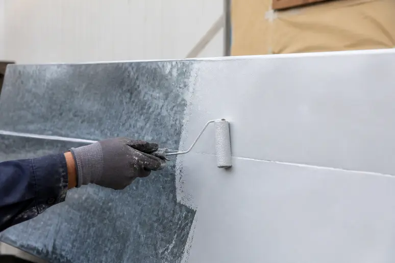 Application d'un primaire d'accrochage sur de la peinture galvanisé avec un rouleau pour assurer l'adhérence.