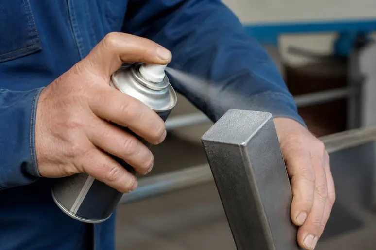 Application d'un spray de galvanisation sur la coupe d'un poteau galvanisé.