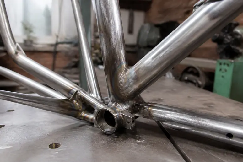 Cadre de vélo métallique sur établi d'atelier avant un thermolaquage au prix spécifique