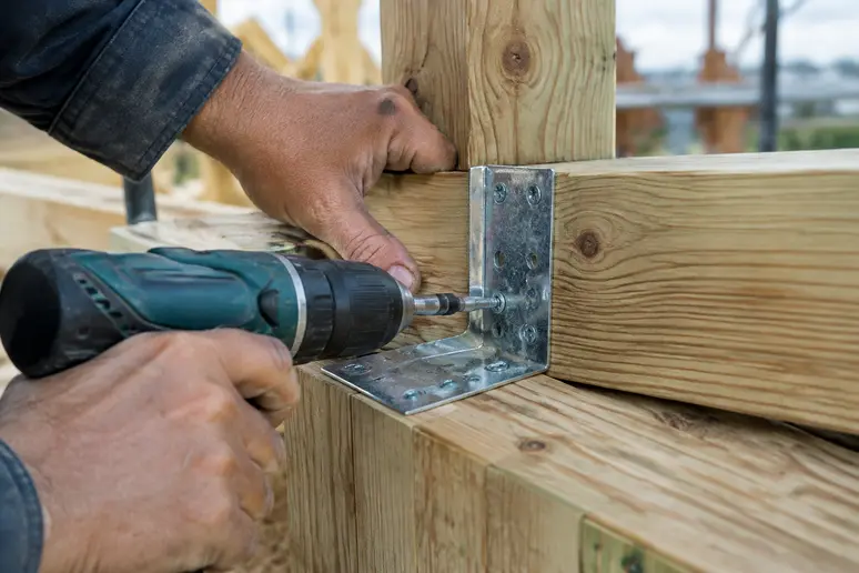 Pose d'un connecteur charpente en angle sur une ossature bois en chantier