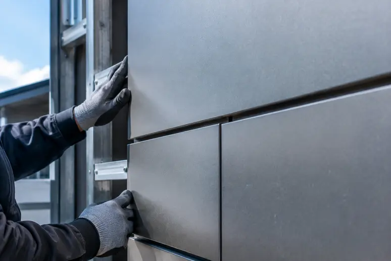 Pose de cassettes métalliques de bardage sur une façade extérieure avec fixations invisibles.
