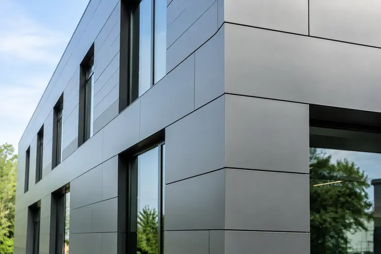 Détail d'une façade moderne habillée de bardage à cassettes avec fixations invisibles.