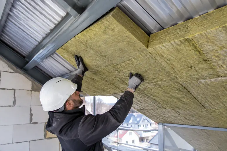 Pose de laine de roche sous une toiture en bac acier pour limiter les nuisances sonores