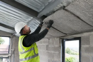 Pose d'une isolation acoustique sous un toit en métal pour atténuer le bruit pluie bac acier.