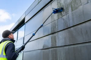 Un technicien nettoie les panneaux extérieurs lors d'un entretien bardage métallique sur un bâtiment