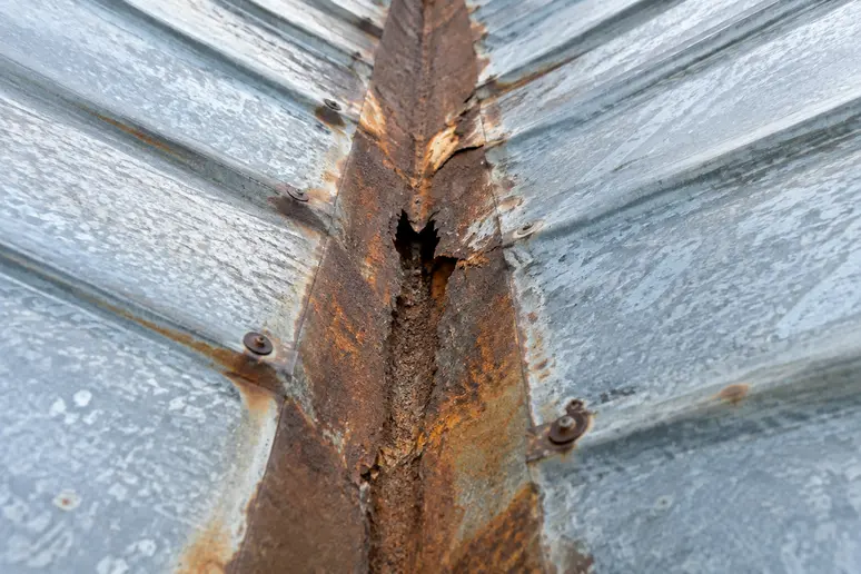 Bande de noue en zinc perforée présentant des traces d'oxydation sur la ligne d'écoulement.
