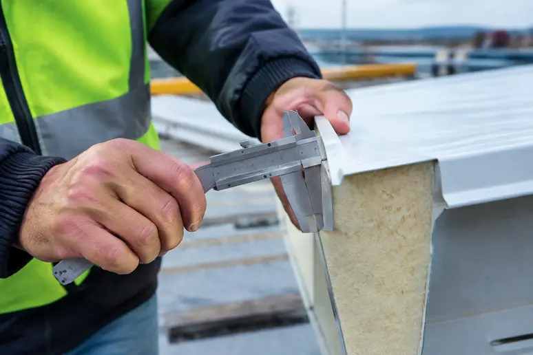 Mesure de l'épaisseur d'un panneau sandwich de toiture avec un outil de contrôle sur chantier